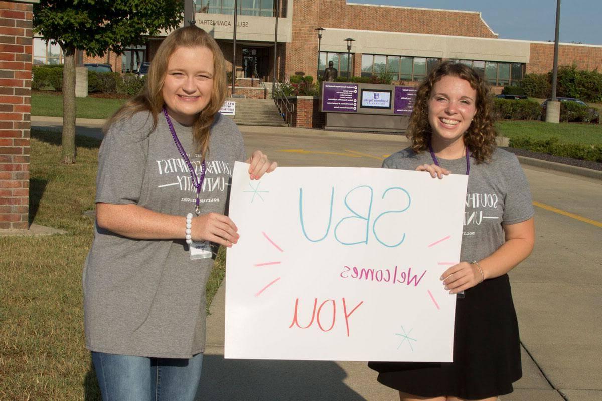 两个女大学生举着海报，上面写着SBU欢迎你